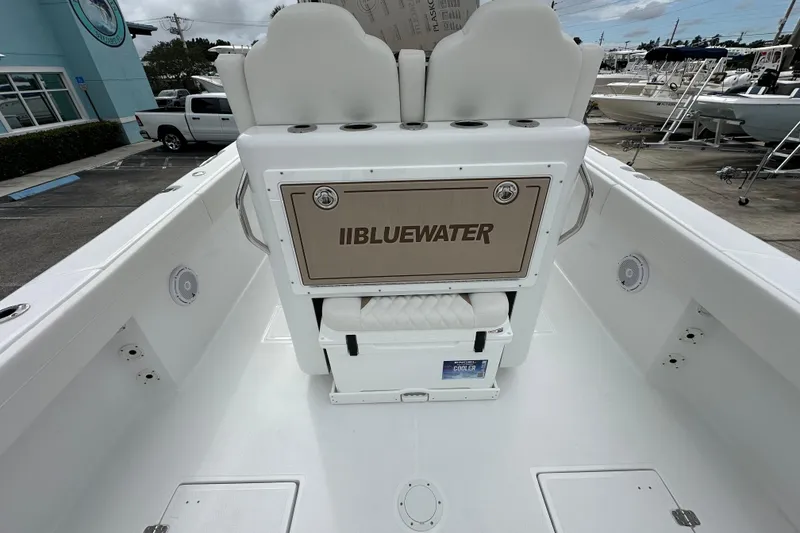 Slide: The Image of 2026 Bluewater 2850 boat interior with seating and storage, docked outdoors. - 18
