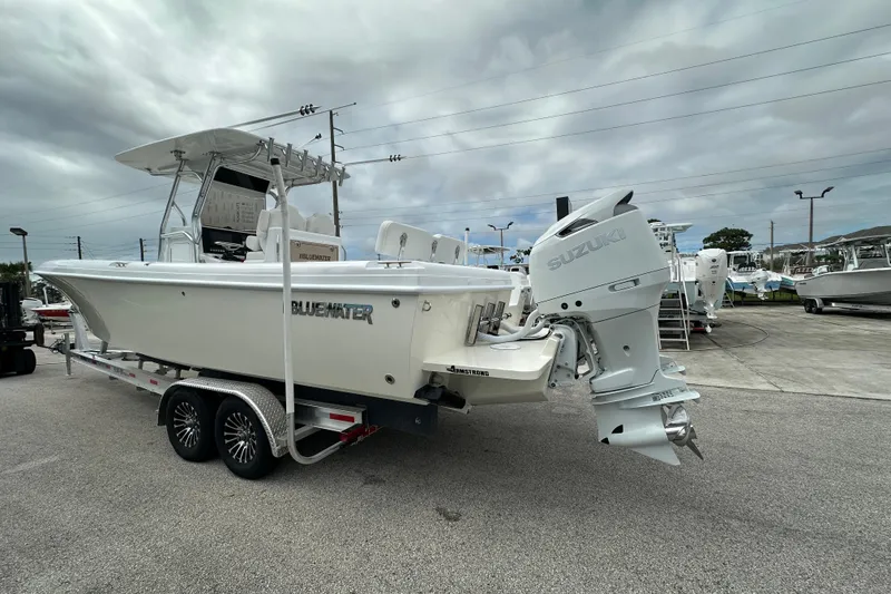 Slide: The Image of 2026 Bluewater 2850 boat with Suzuki outboard motor on a trailer, parked outdoors. - 4