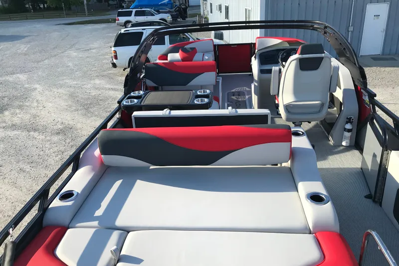 Slide: The Image of 2026 Avalon LSZ Entertainer boat interior with red and gray seating, table, and steering console. - 16