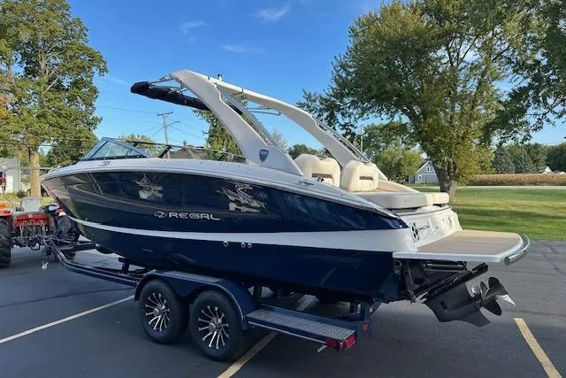 Slide: The Image of 2026 Regal LS6 boat on trailer, parked outdoors, with trees and blue sky background. - 3
