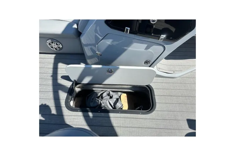 Slide: The Image of 2024 Manitou LX 25 SRS boat storage compartment with open lid on deck. - 28
