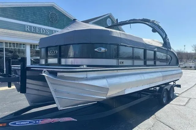 Slide: The Image of 2024 Manitou LX 25 SRS pontoon boat on trailer outside a building. - 40