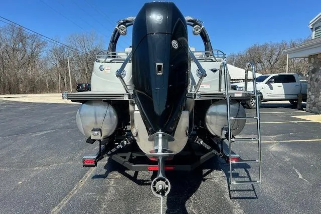 Slide: The Image of 2024 Manitou LX 25 SRS pontoon boat with outboard motor, parked on asphalt. - 6