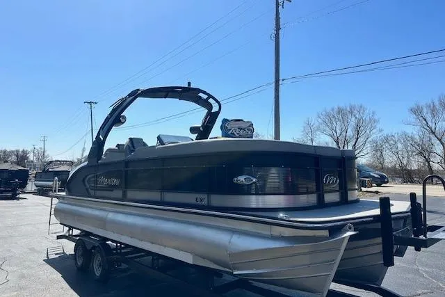 Slide: The Image of 2024 Manitou LX 25 SRS pontoon boat on trailer, parked outdoors under clear sky. - 8