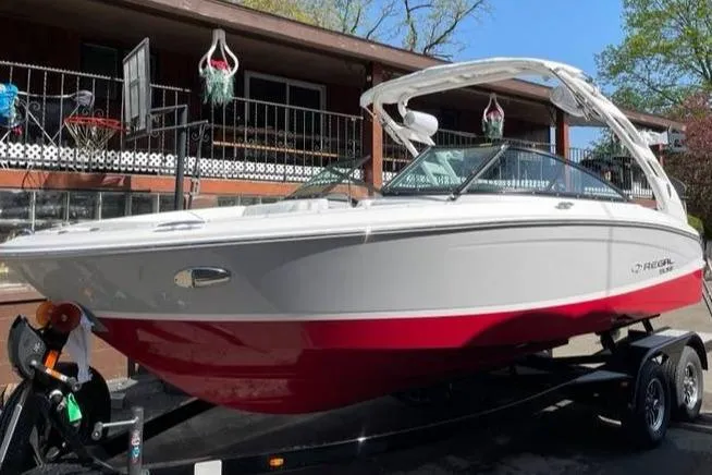 The Image of 2025 Regal LS2 Surf boat with red and white design on a trailer. - 0