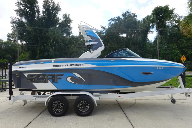 Slide: The Image of 2017 Centurion Ri217 boat in blue and gray on a trailer, parked outdoors. - 5