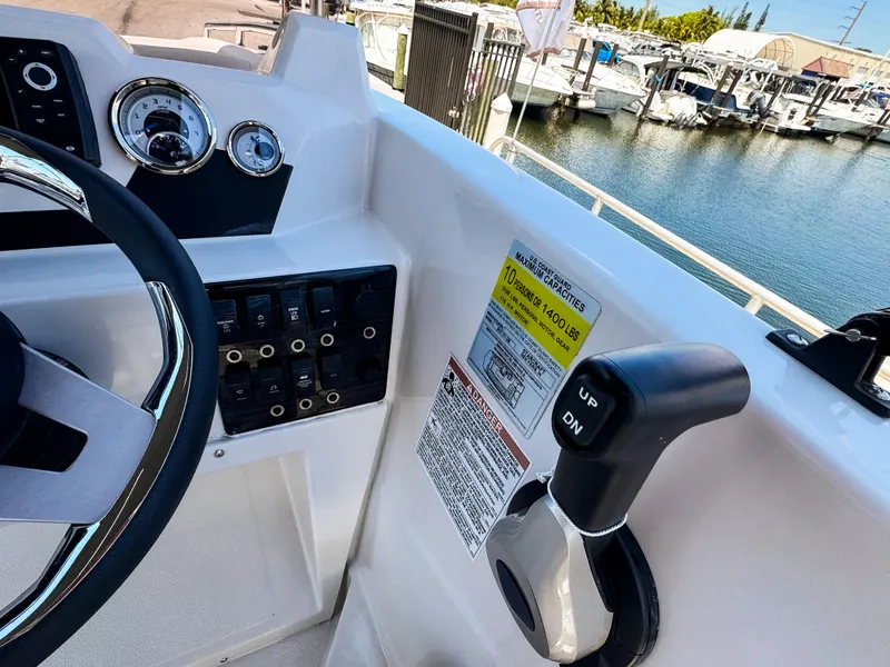 Slide: The Image of 2023 Starcraft SVX 171 OB boat dashboard with controls and gauges by a marina. - 14