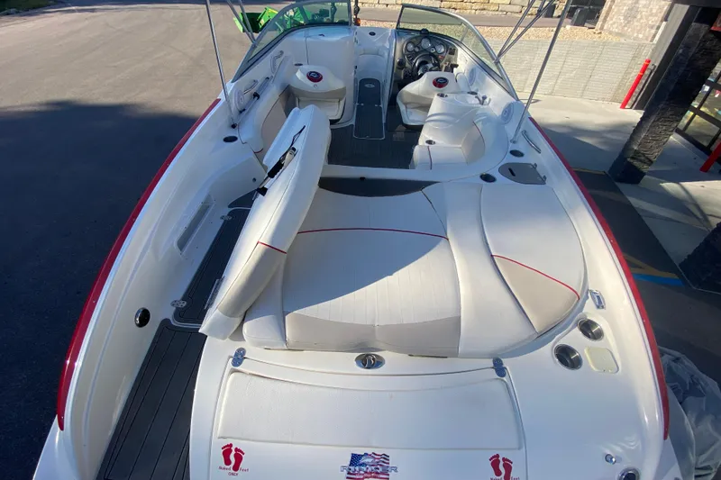 Slide: The Image of 2008 Rinker 246 Captiva Bowrider with white seating and red accents, docked outdoors. - 4