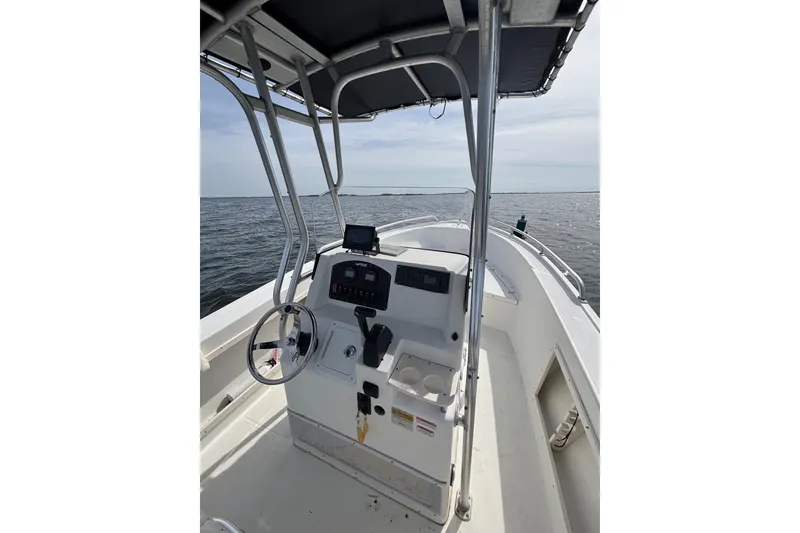 Slide: The Image of 2008 Mako 212 Center Console boat on open water, featuring steering console and canopy. - 19