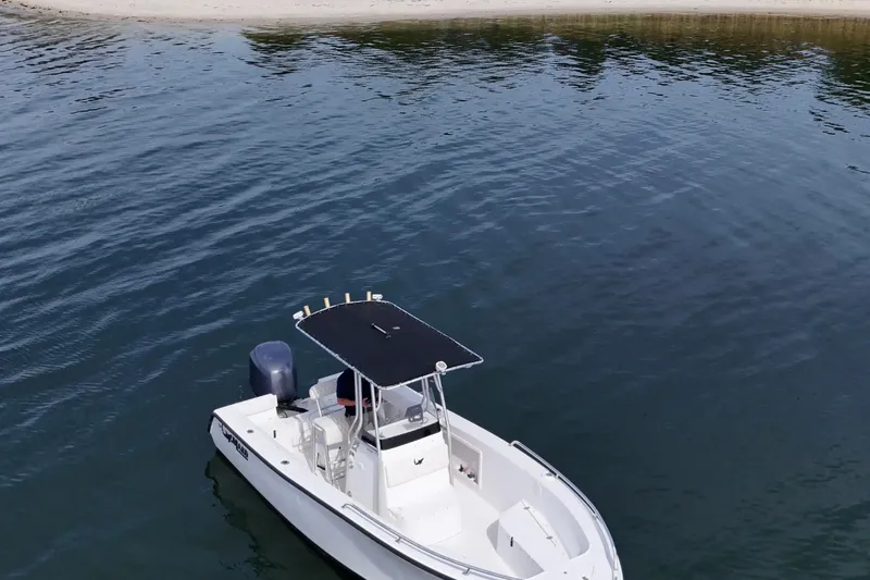 Slide: The Image of 2008 Mako 212 Center Console boat on calm water near a sandy shore. - 24