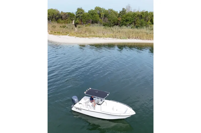 Slide: The Image of 2008 Mako 212 Center Console boat on calm water near a sandy shoreline. - 25