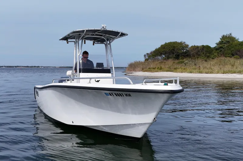 Slide: The Image of 2008 Mako 212 Center Console boat on calm water near a sandy shoreline. - 8