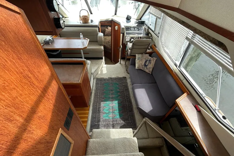 Slide: The Image of 1997 Bayliner 3587 Motoryacht interior with seating, table, and helm, featuring wood accents. - 19