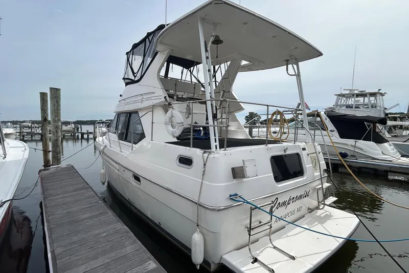 Slide: The Image of 1997 Bayliner 3587 Motoryacht docked at marina, rear view with canopy and lifebuoy. - 3