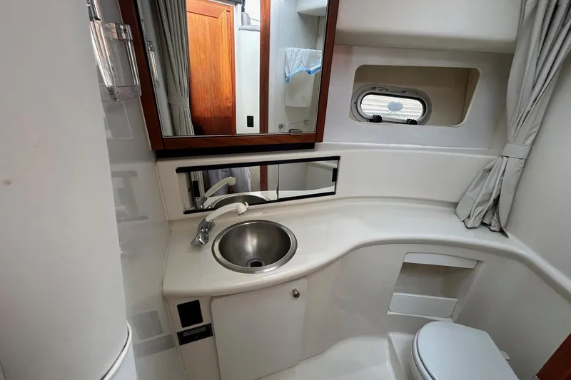 Slide: The Image of Bathroom interior of 1997 Bayliner 3587 Motoryacht with sink, mirror, and porthole window. - 31