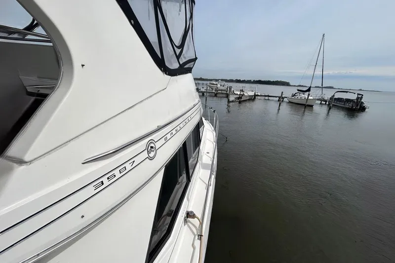 Slide: The Image of 1997 Bayliner 3587 Motoryacht docked at a marina with sailboats in the background. - 7