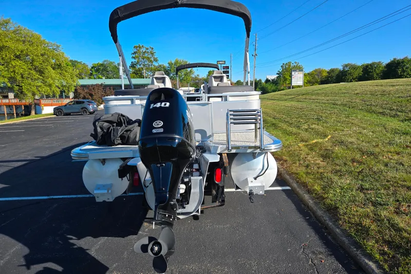 Slide: The Image of 2023 Avalon LSZ Quad Lounger pontoon boat with 140 HP engine, parked outdoors. - 2