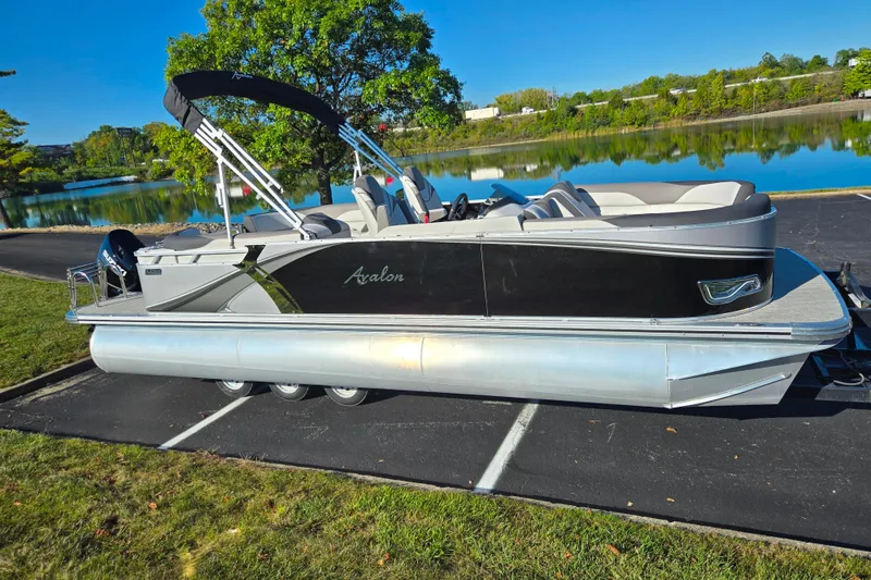 Slide: The Image of 2023 Avalon LSZ Quad Lounger pontoon boat parked by a scenic lake. - 9
