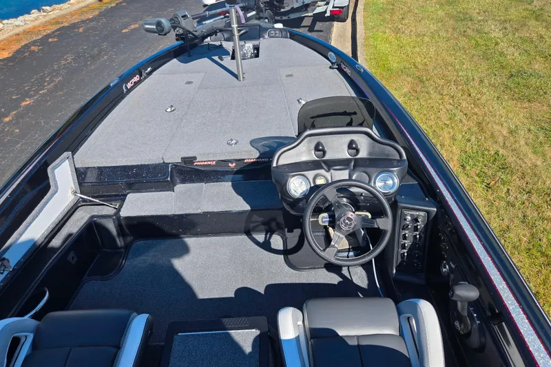 Slide: The Image of 2022 Phoenix 919 ProXP boat interior with steering wheel and seating, parked on grass. - 11