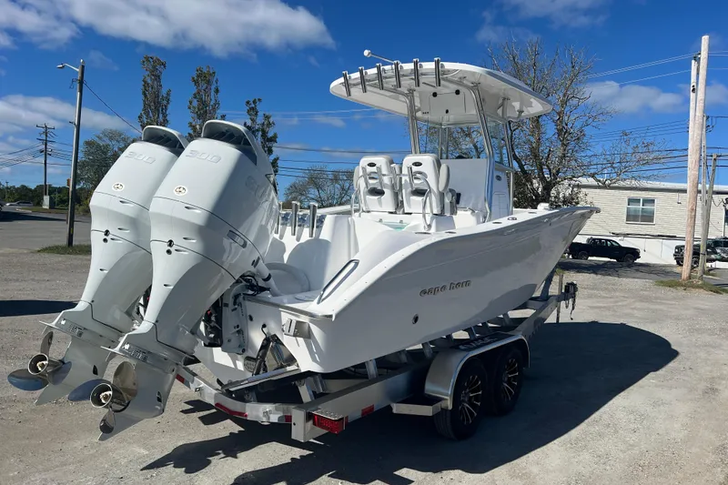 Slide: The Image of 2026 Cape Horn 27XS boat with dual engines on a trailer, parked outdoors. - 2