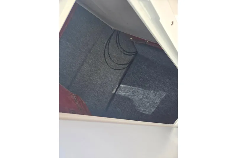 Slide: The Image of Storage compartment inside 2018 Yamaha Boats AR240, featuring carpeted interior and wiring. - 16