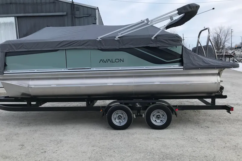 Slide: The Image of 2026 Avalon Venture Quad Lounger 19' pontoon boat on trailer, covered and parked outdoors. - 4