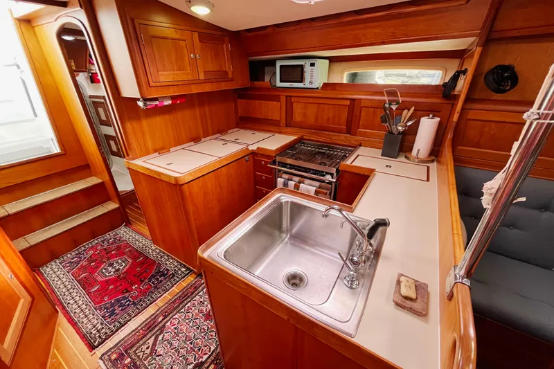 Slide: The Image of 1995 Able Apogee 50 yacht kitchen with wooden cabinetry, sink, stove, and microwave. - 15