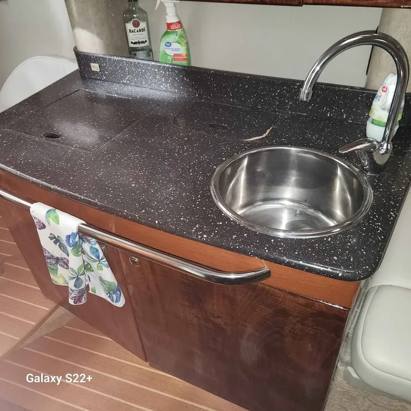 Slide: The Image of 2006 Formula 27 PC boat kitchenette with black countertop, stainless steel sink, and cleaning supplies. - 12