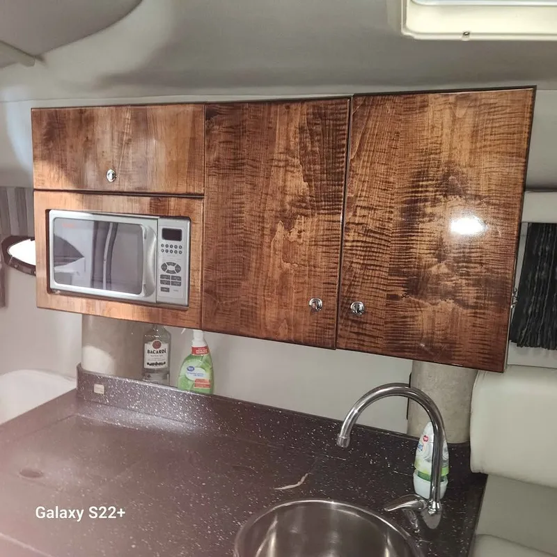 Slide: The Image of 2006 Formula 27 PC boat kitchen with wooden cabinets, microwave, and sink. - 16