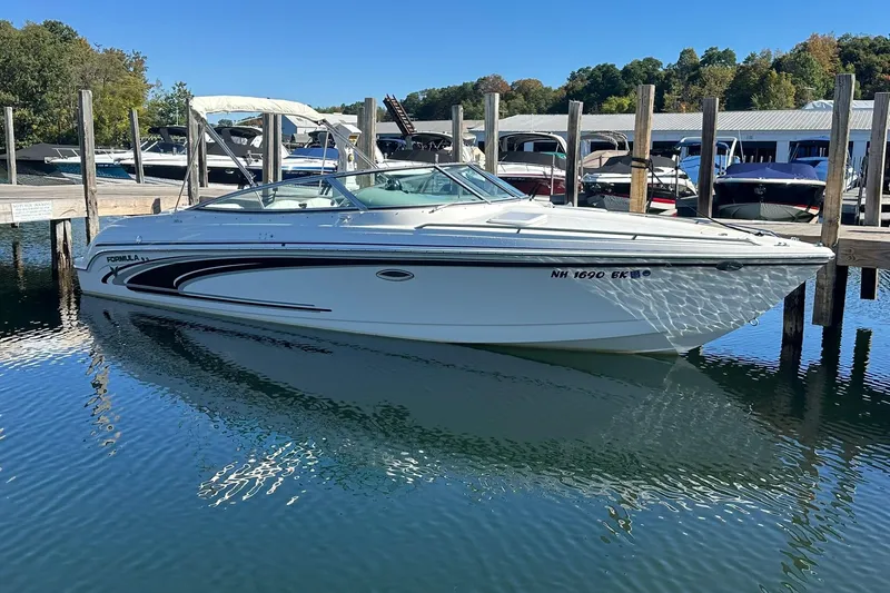 Slide: The Image of 2005 Formula 260 Sun Sport boat docked in a marina, surrounded by calm water. - 2