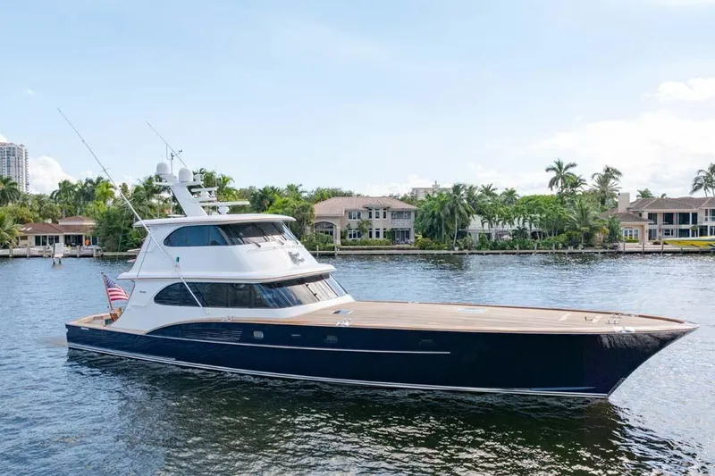 The Image of 1984 Feadship Yacht Fish cruising on a scenic waterway with palm trees and luxury homes. - 1