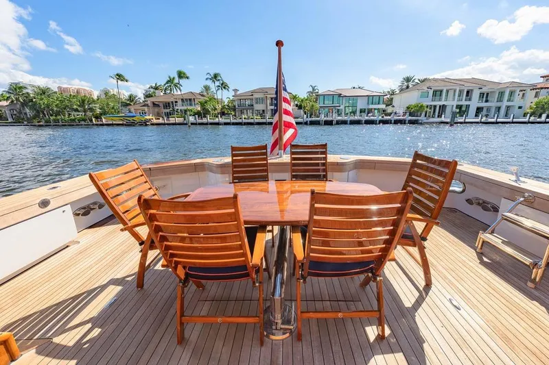 Slide: The Image of Outdoor dining area on 1984 Feadship Yacht Fish, featuring wooden chairs and table, with waterfront view. - 3