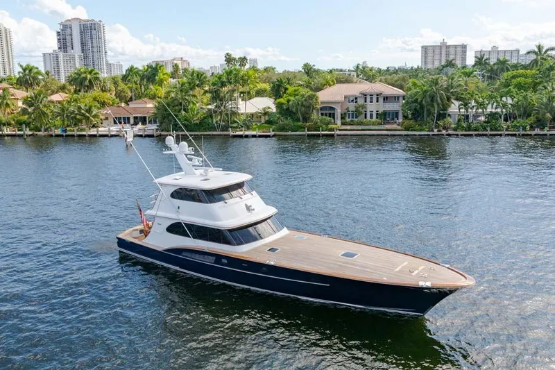 Slide: The Image of 1984 Feadship Yacht Fish cruising on a scenic waterway with luxury homes in the background. - 44