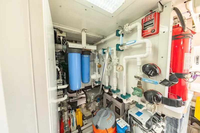Slide: The Image of Engine room of 1984 Feadship Yacht Fish, featuring pipes, gauges, and fire safety equipment. - 55