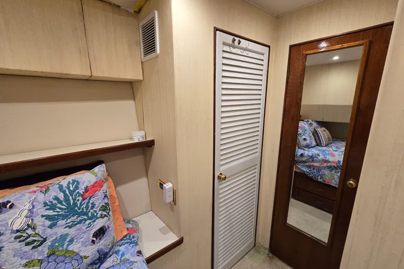 Slide: The Image of Cozy cabin interior of 1982 Ocean Yachts 55 Super Sport, featuring vibrant bedding and mirrored door. - 24