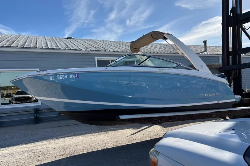 Slide: The Image of 2021 Regal 23 OBX boat in blue, displayed outdoors on a lift. - 0