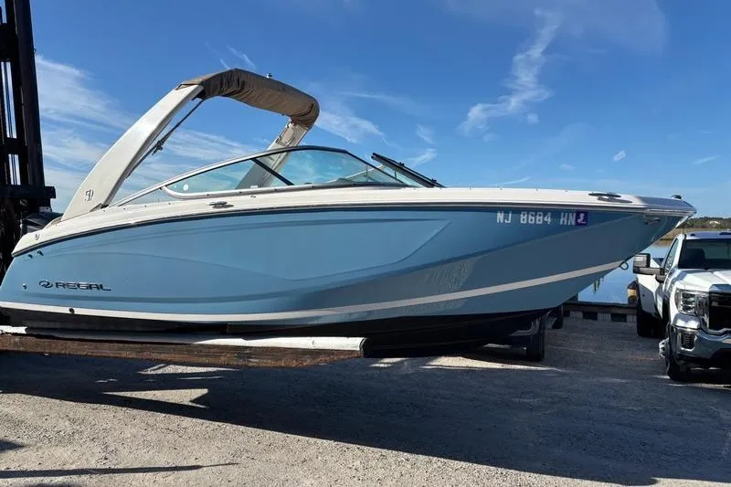 Slide: The Image of 2021 Regal 23 OBX boat in light blue, docked under a clear blue sky. - 6