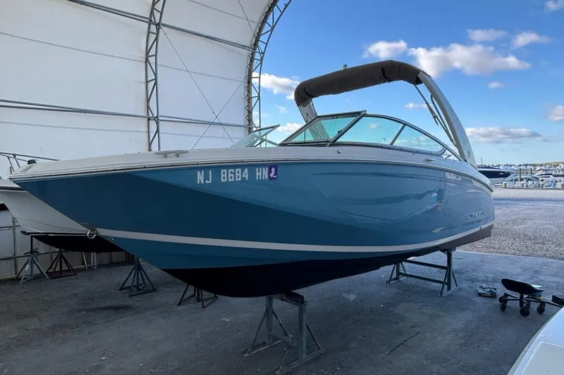 Slide: The Image of 2021 Regal 23 OBX boat in storage, blue hull, covered marina setting. - 9
