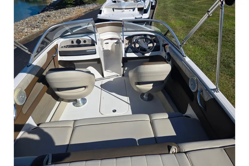 Slide: The Image of 2015 Bayliner 185 Bowrider interior with seating, steering wheel, and dashboard, near water. - 10
