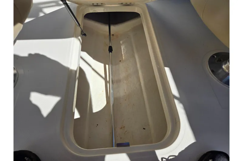 Slide: The Image of 2015 Bayliner 185 Bowrider storage compartment, open and empty, with sunlight casting shadows. - 12