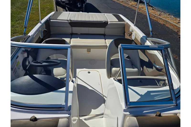 Slide: The Image of 2015 Bayliner 185 Bowrider interior with seating and steering wheel, near water. - 18