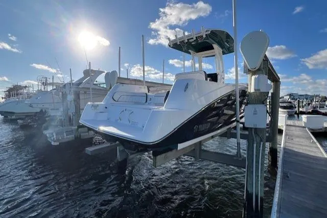 Slide: The Image of 2021 Yama 252 FSH Sport boat docked at marina under clear blue sky. - 2