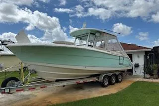 Slide: The Image of 2021 Robalo R300 Center Console boat on trailer, parked in driveway under cloudy sky. - 1