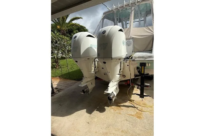 Slide: The Image of 2021 Robalo R300 Center Console with twin outboard engines in a driveway setting. - 9