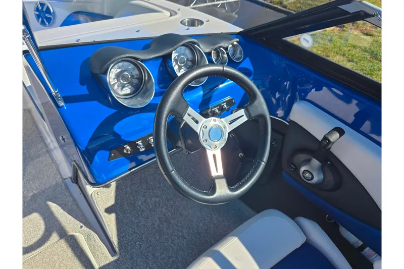 Slide: The Image of 2013 Glastron GT 205 boat dashboard with blue accents and steering wheel. - 14