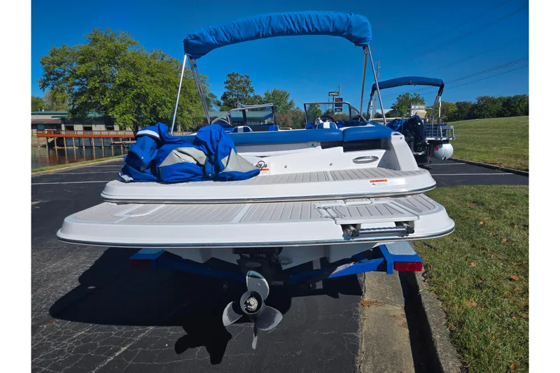 Slide: The Image of 2013 Glastron GT 205 boat with blue canopy, parked on a sunny day. - 2