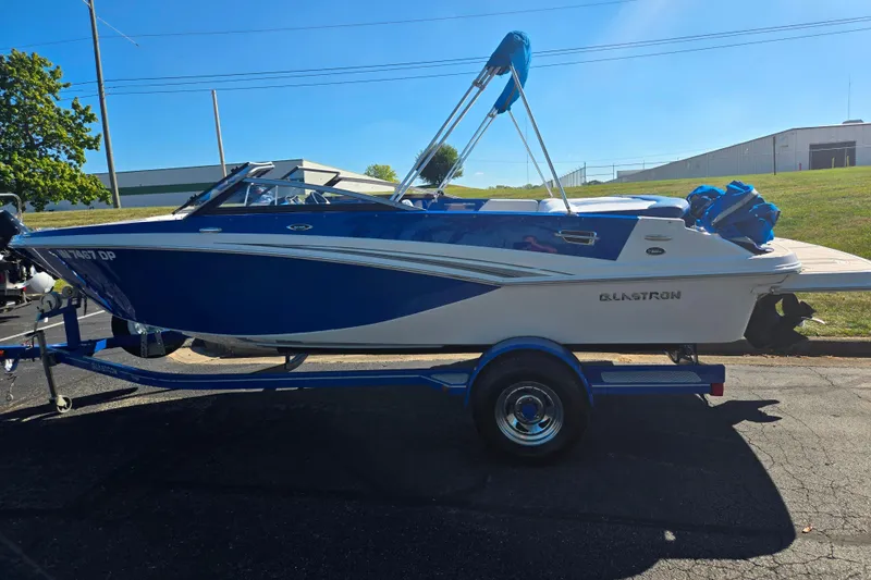 Slide: The Image of 2013 Glastron GT 205 boat in blue and white on a trailer, parked outdoors. - 4