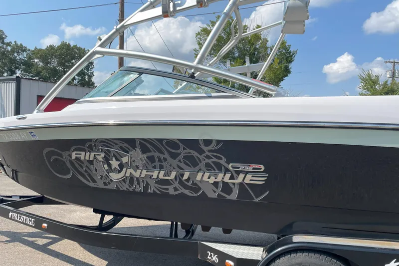 Slide: The Image of 2009 Nautique Super Air Nautique 230 boat on trailer, side view with graphics. - 2