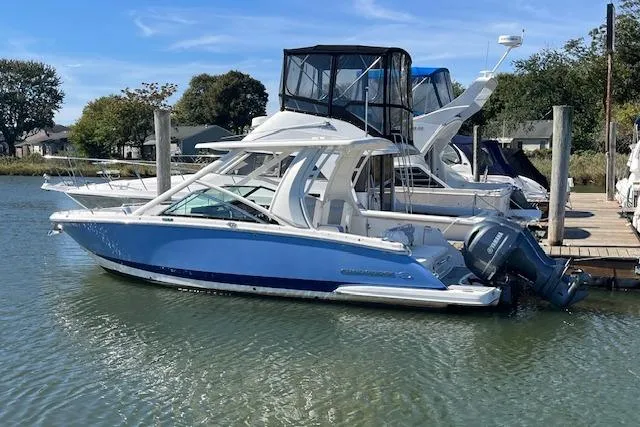 Slide: The Image of 2023 Chaparral 280 OSX boat docked in a marina, featuring a sleek blue and white design. - 0