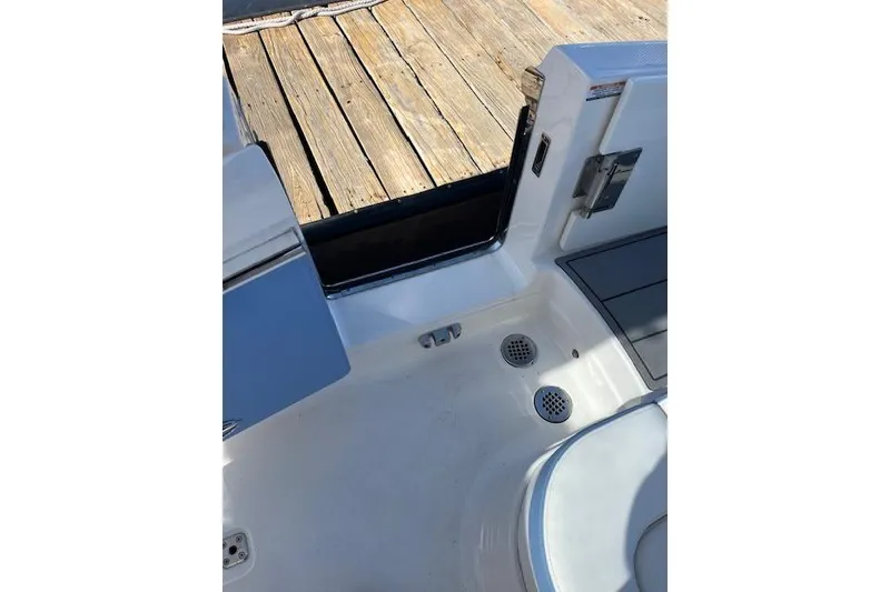 Slide: The Image of 2023 Chaparral 280 OSX boat interior near dock, showcasing seating and deck details. - 15